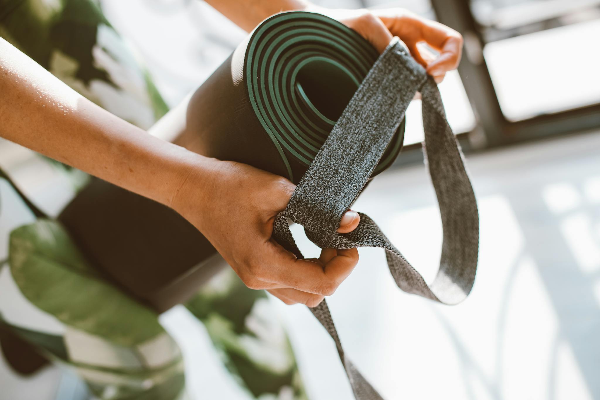 Close-up of a woman's hands holding a yoga mat with a strap. Perfect for fitness and lifestyle concepts.